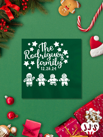 A festive Christmas napkin featuring a gingerbread family enjoying the holiday season, with options to customize with a family name and a custom message.