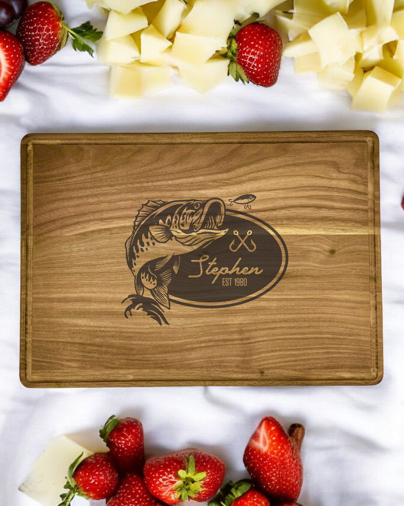 A personalized walnut cutting board featuring a detailed fishing scene, with your name engraved on the bottom.