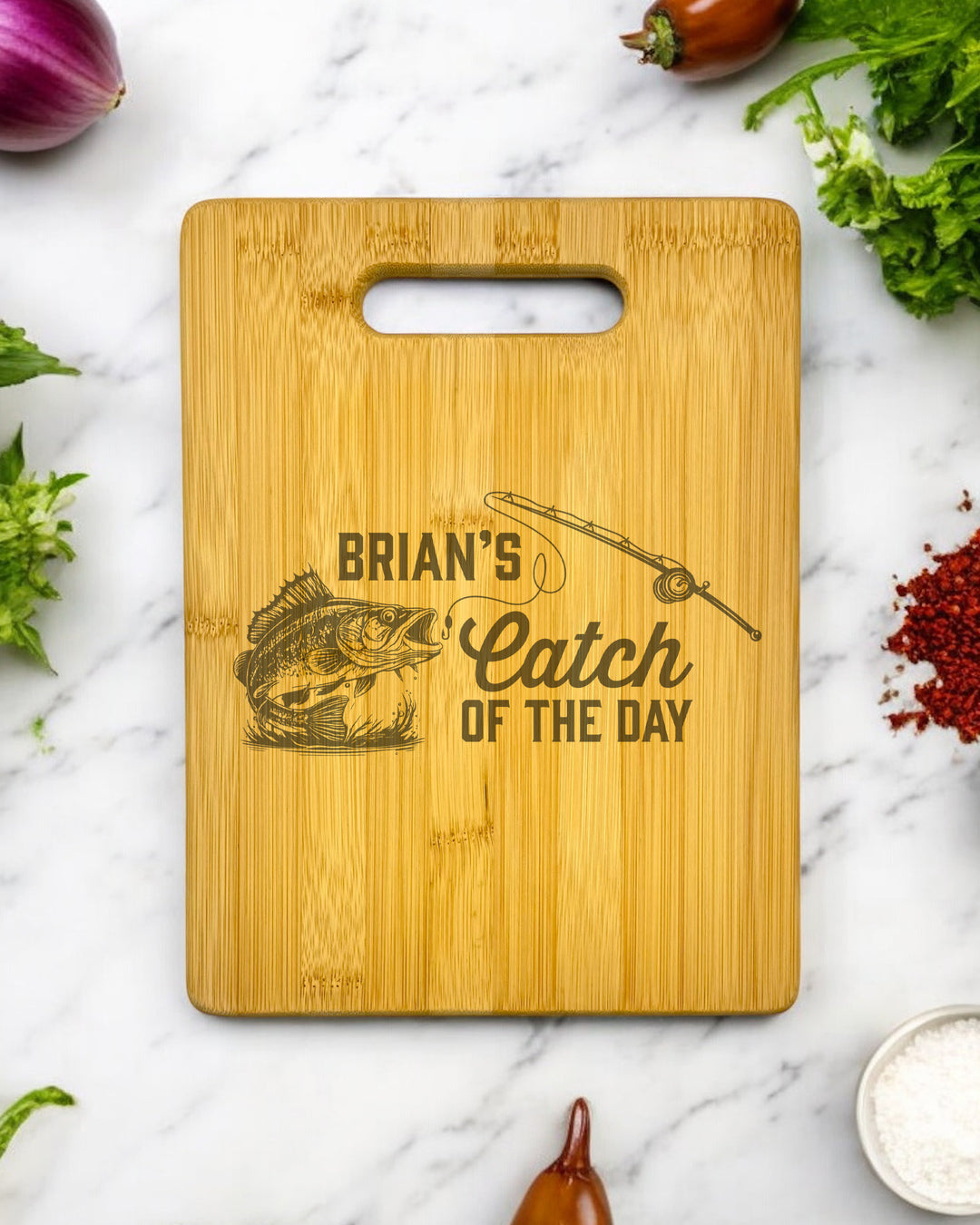 A personalized bamboo cutting board with a "Catch of the Day" design and engraved text.