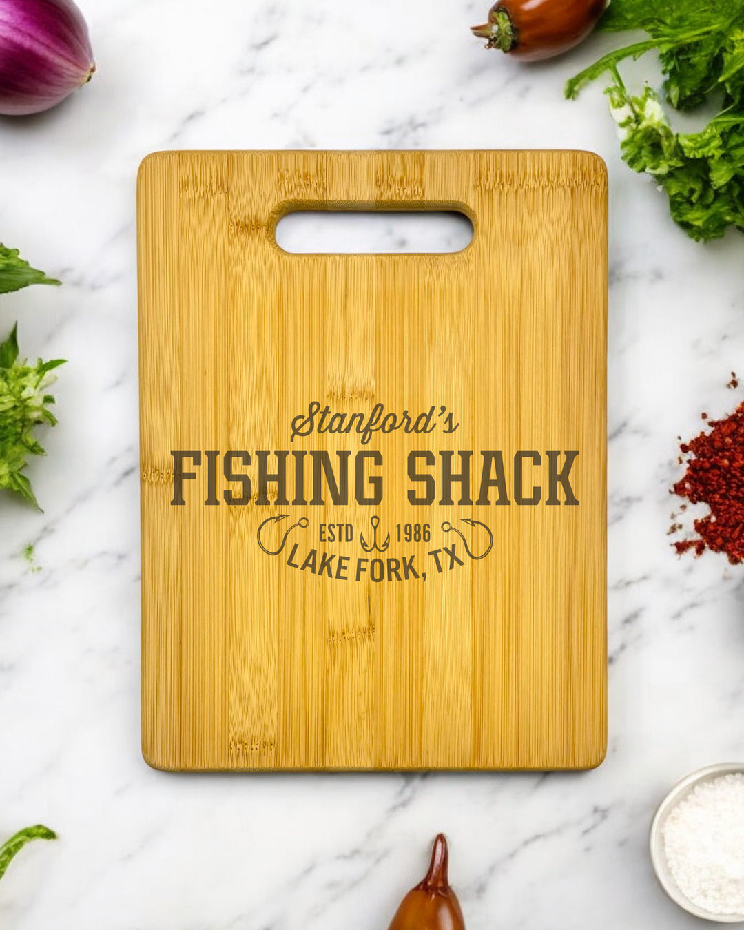 A personalized bamboo cutting board with a charming fishing shack illustration. The board is ideal for kitchen use and features a name or initials.